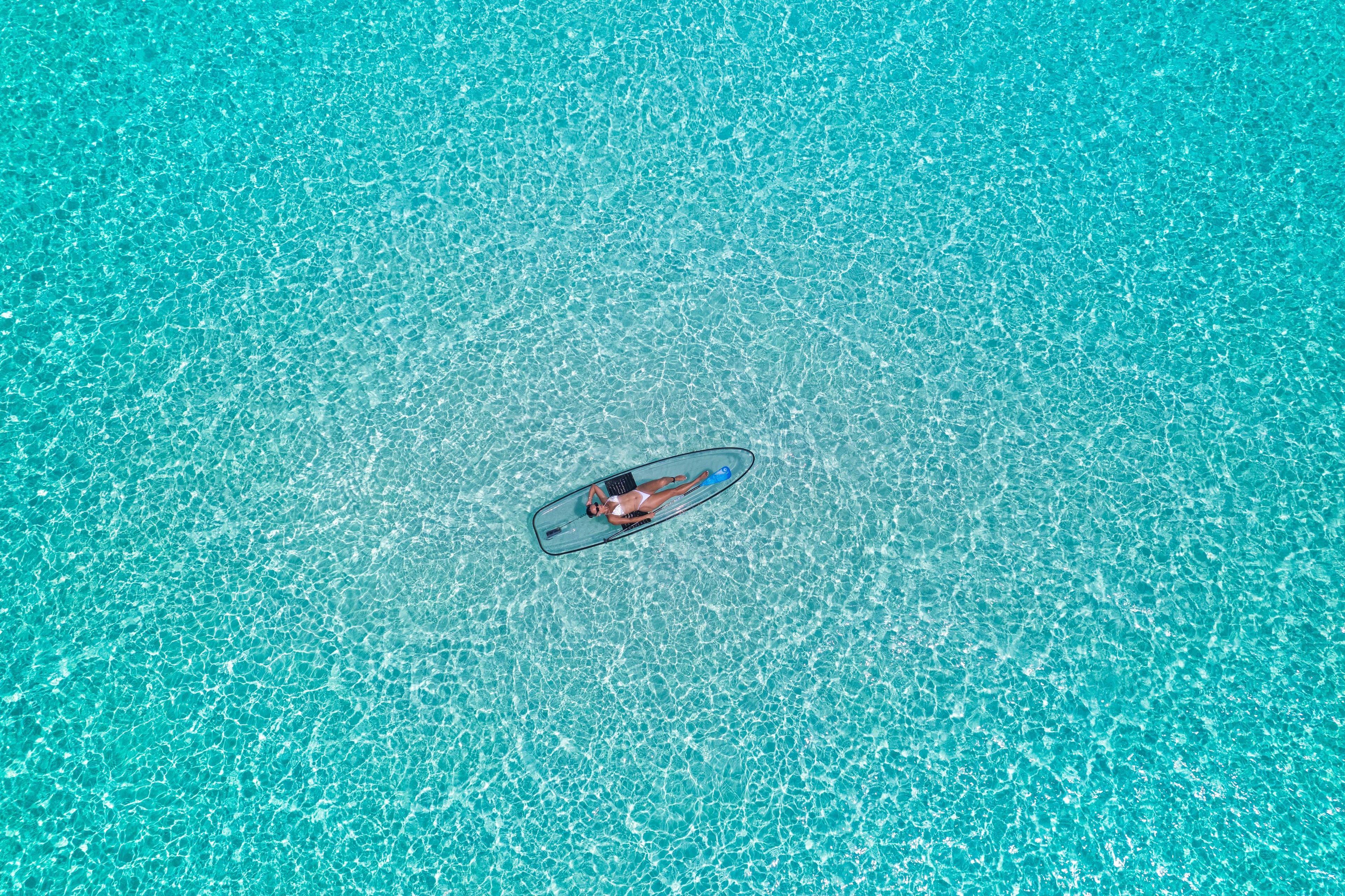 Crystal clear turquoise Maldives lagoon aerial view at Soneva Jani transparent paddleboard on pristine Indian Ocean waters